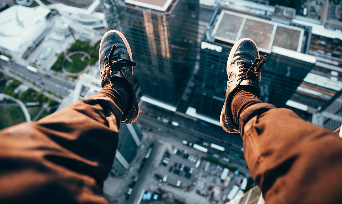 Feet dangling off a building above a city