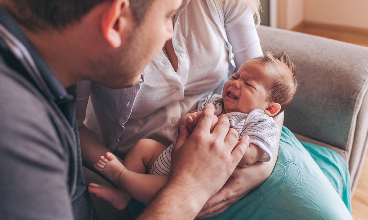 A man and woman holding a crying infant