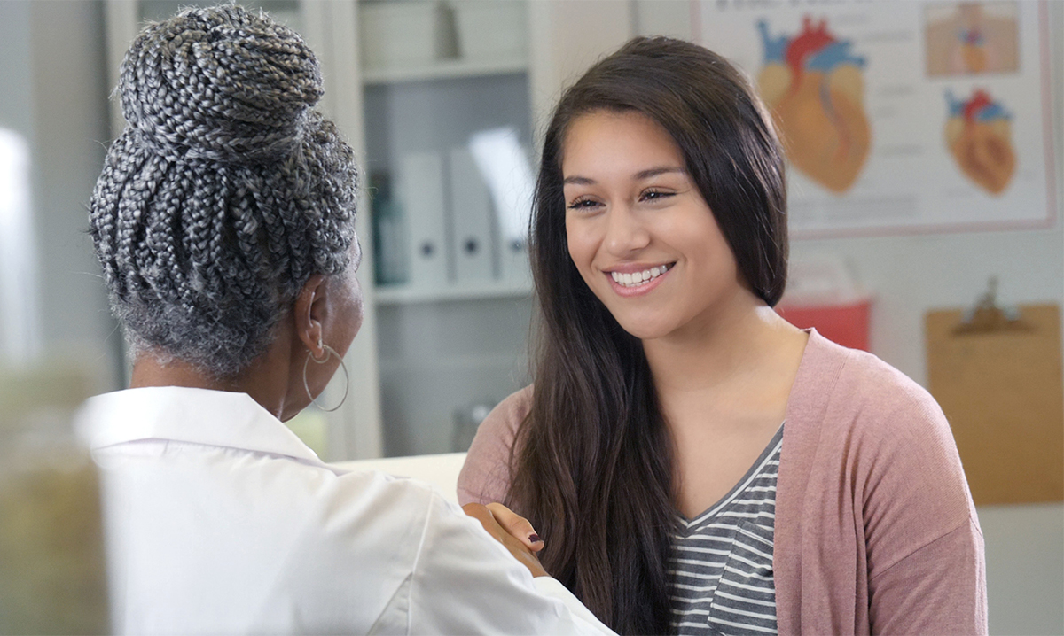 Attentive teenage girl talks with female doctor