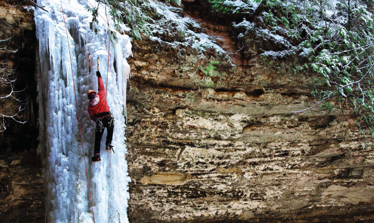 A person climbing a frozen waterfall in michigan