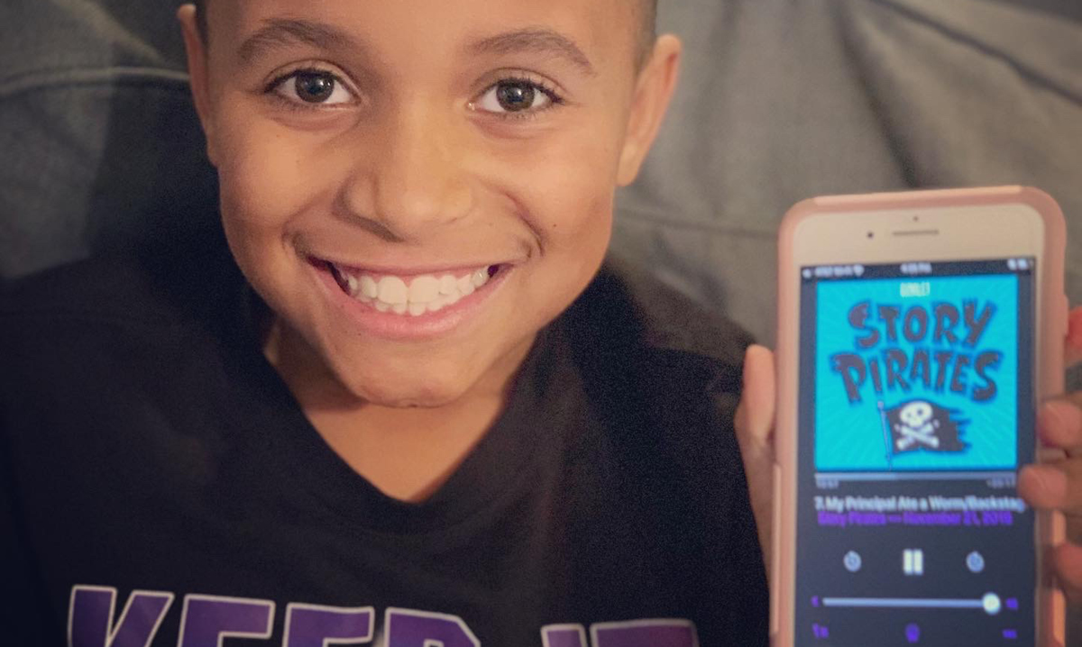 Boy holding up phone with the story pirates logo on it