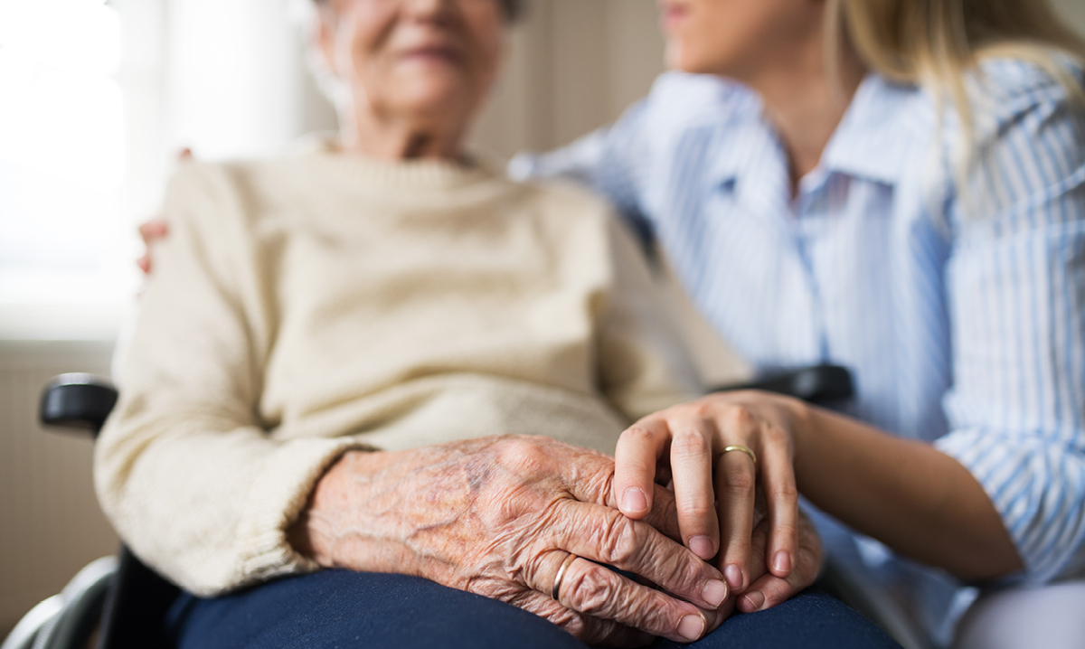Woman touching older person's hand