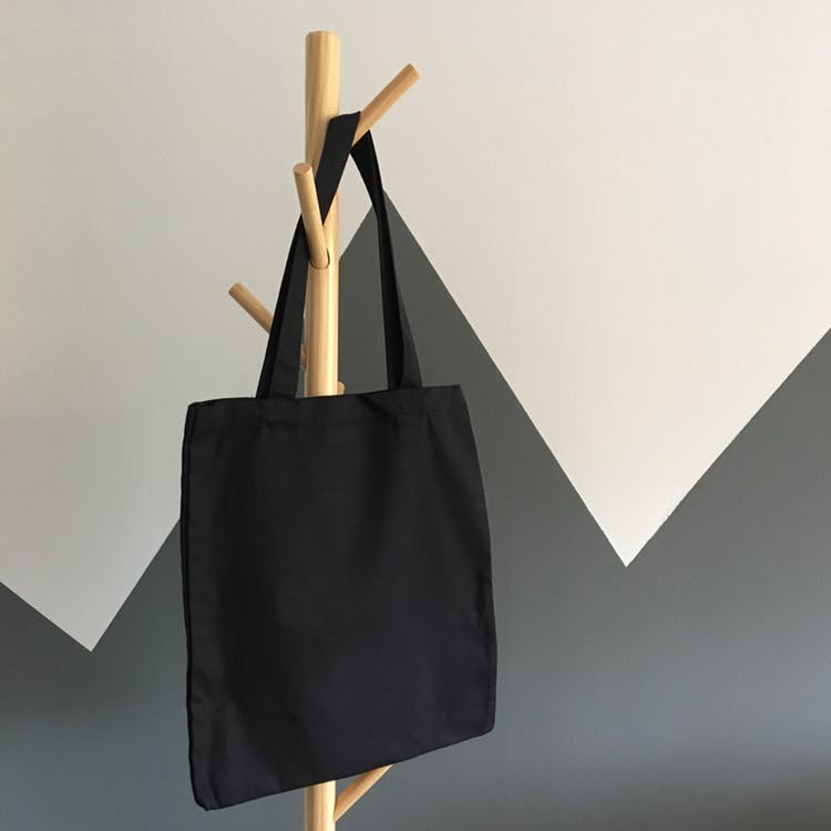 black tote bag on a rack on a white and grey background