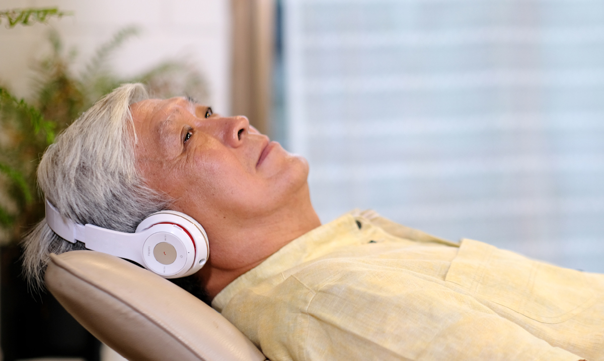 Elderly man laying down listening to headphones