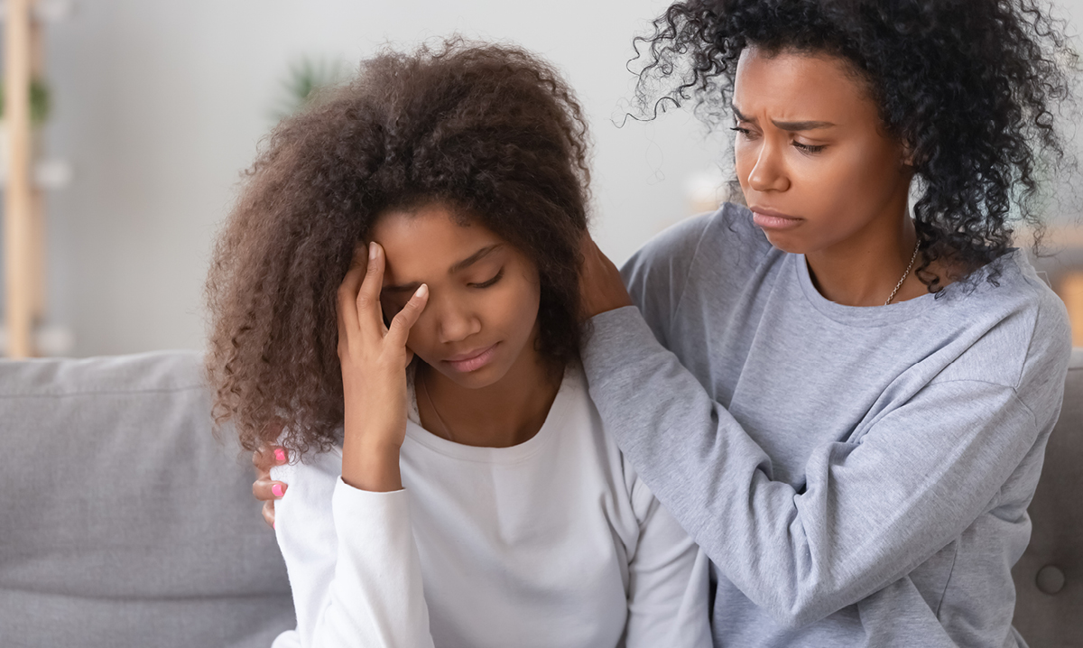 Older woman puts arms around sad looking younger woman