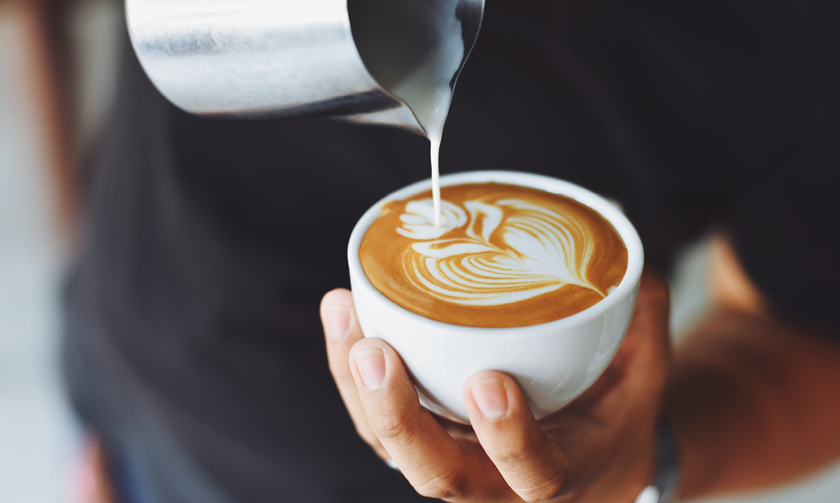 Person pouring a latte