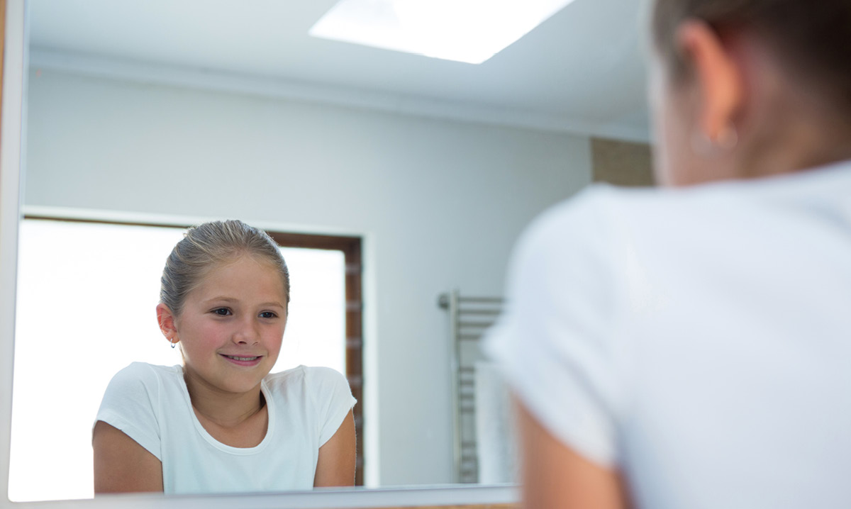 Little girl smiling at herself in the mirror