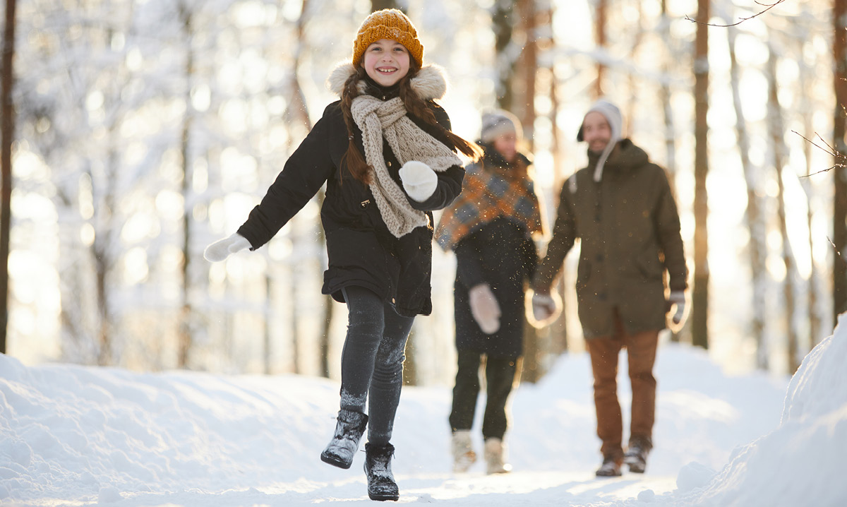 Girl skipping away from her parents in a snowy forest