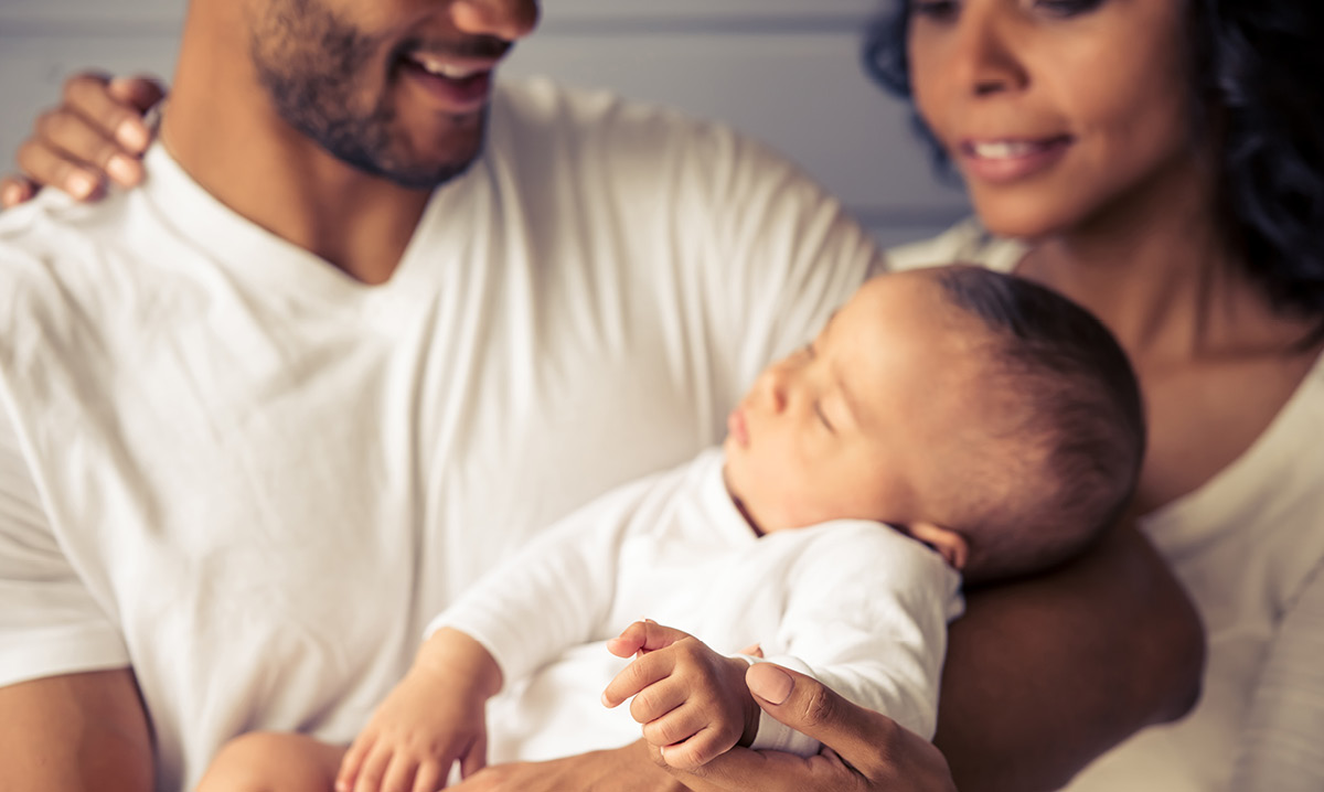A man holding a new baby with a woman standing next to him