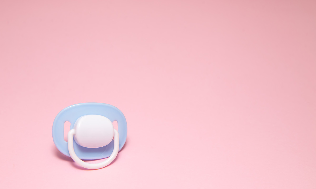 Blue pacifier on a pink background