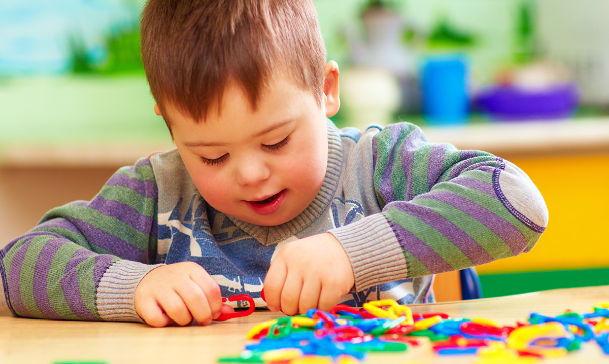 Child with special needs playing with colorful toys