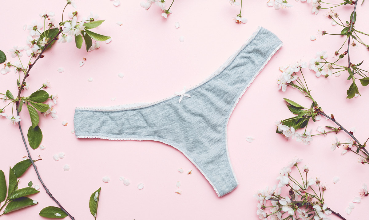 Gray thong on a pink background surrounded by flowers