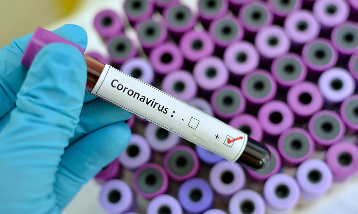 Gloved hand holding a test tube that says caronavirus