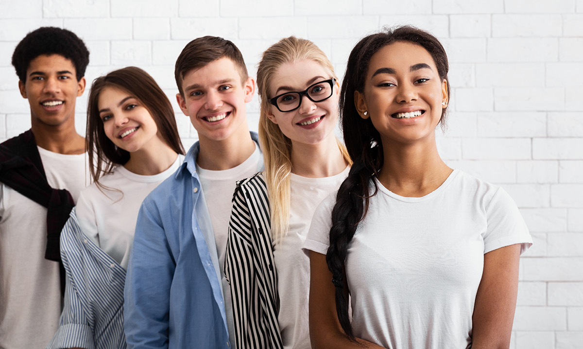 Group of teens standing in front of a white brick wall