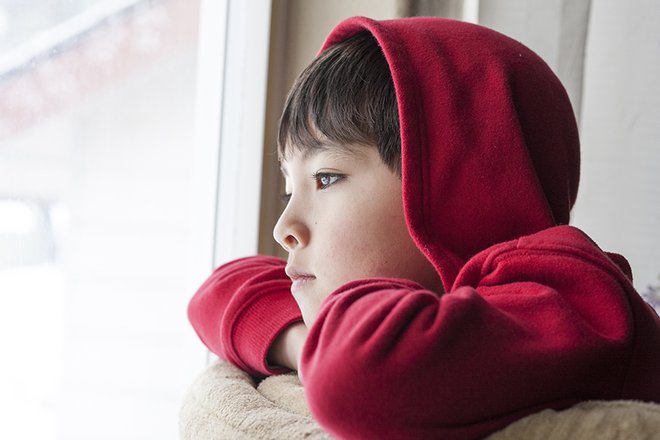 Sad child looking out a window