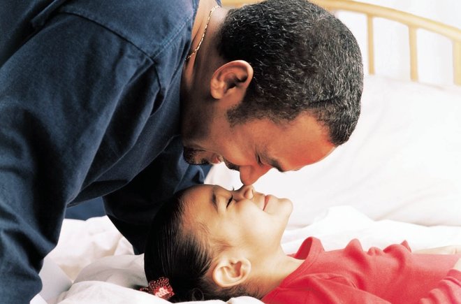 Dad leaning over child while child looks up at dad
