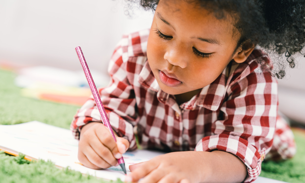 Child coloring with a colored pencil