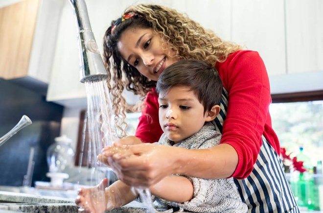 Woman helping a child wash his hands
