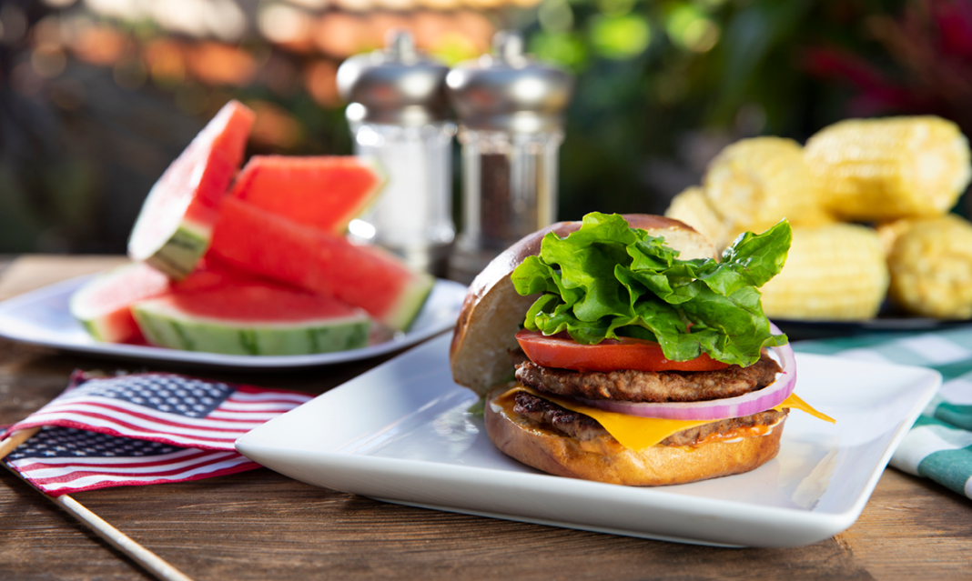 Hamburger, watermelon and corn on a picnic table