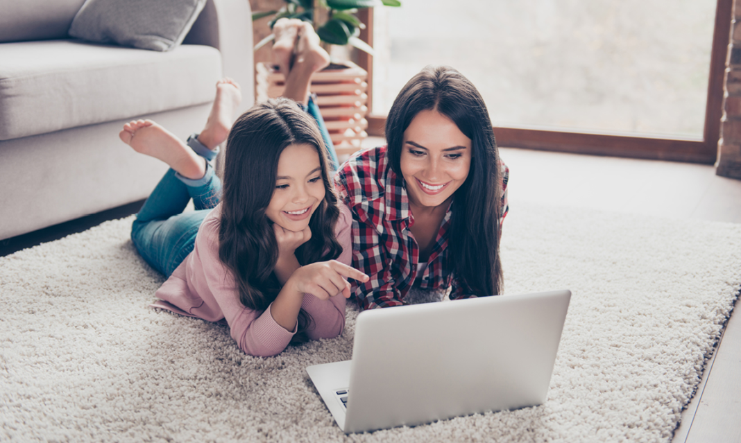 Mom and daughter on a laptop while laying on the floor