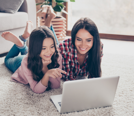 Mom and daughter on a laptop while laying on the floor
