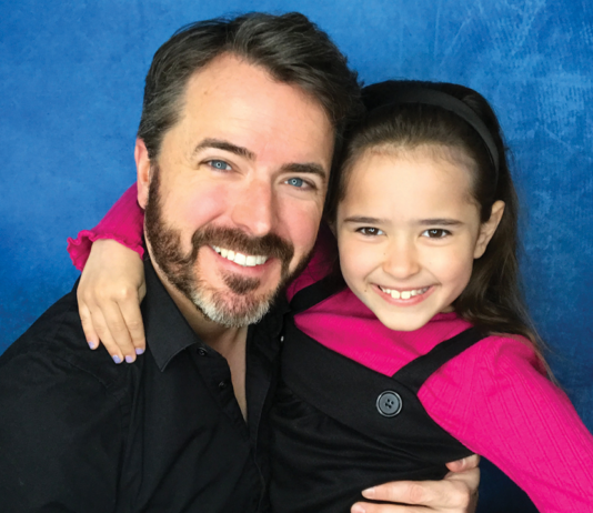 A man and girl smiling on a blue background