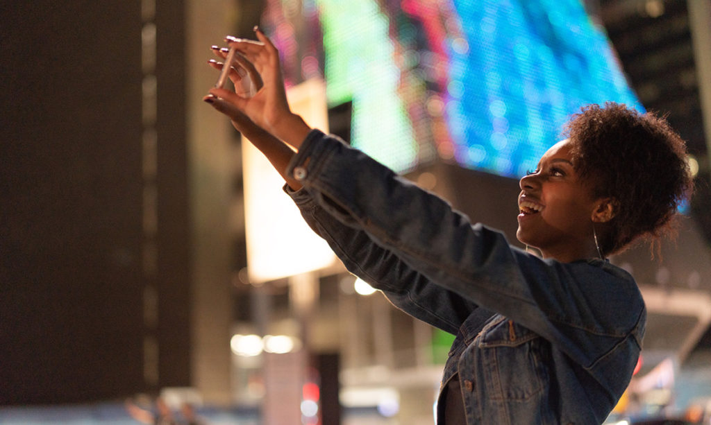 Teen girl taking a photo in a city