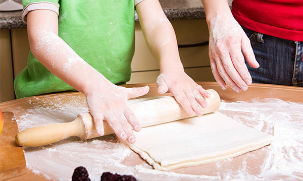 A child rolling out dough with a rolling pin