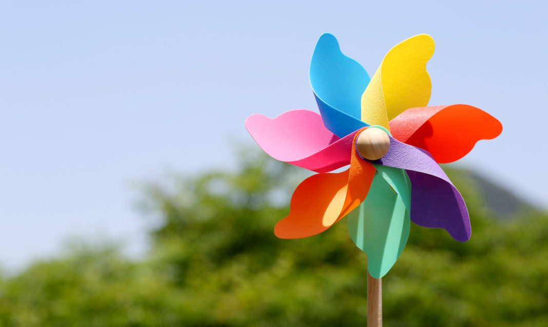 A pinwheel in front of a blue sky and trees