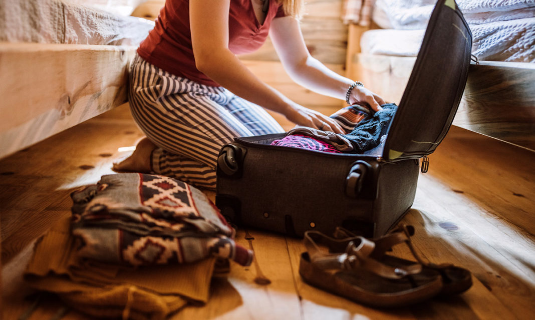 A woman in pajamas packing a suitcase