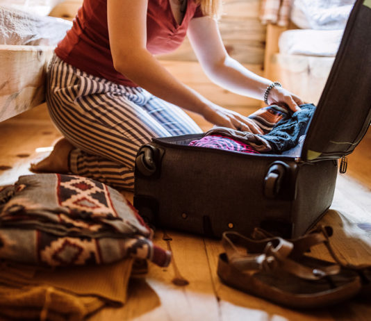 A woman in pajamas packing a suitcase
