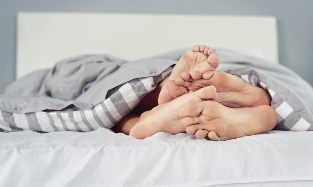 Close up of four feet in bed