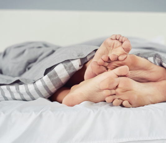 Close up of four feet in bed