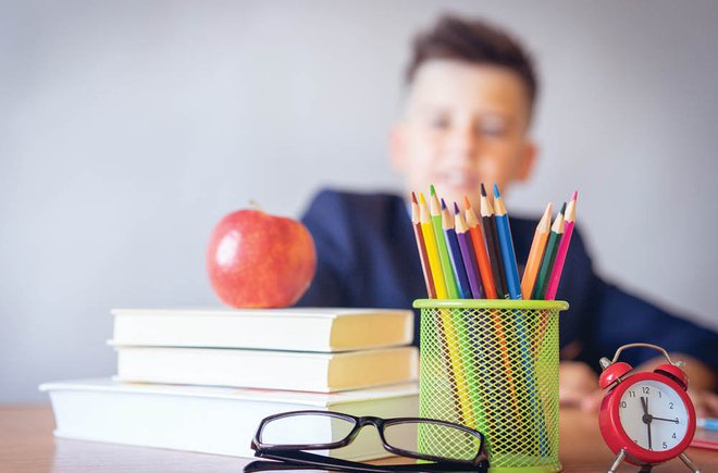 Child sitting behind various school supplies