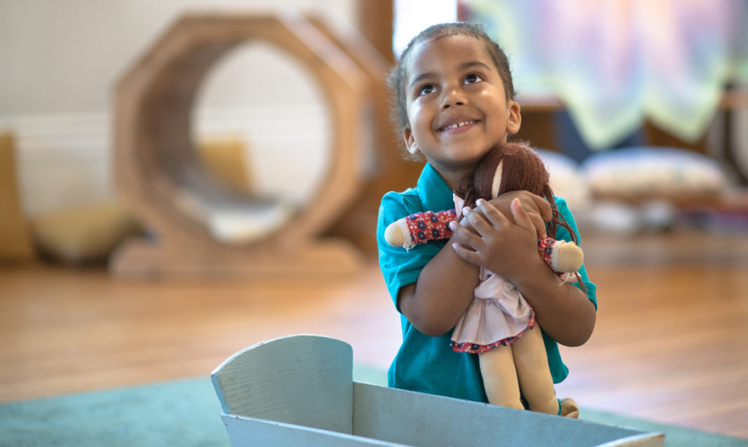 A little Black girl hugging her doll