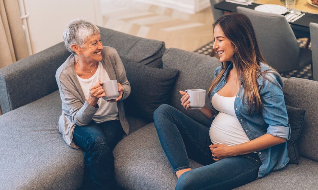Pregnant woman sitting on a couch with an older woman