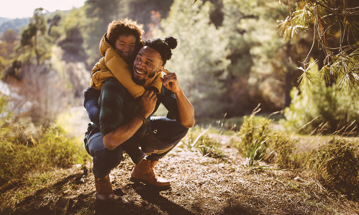 A man giving a child a piggy-back ride up a mountain