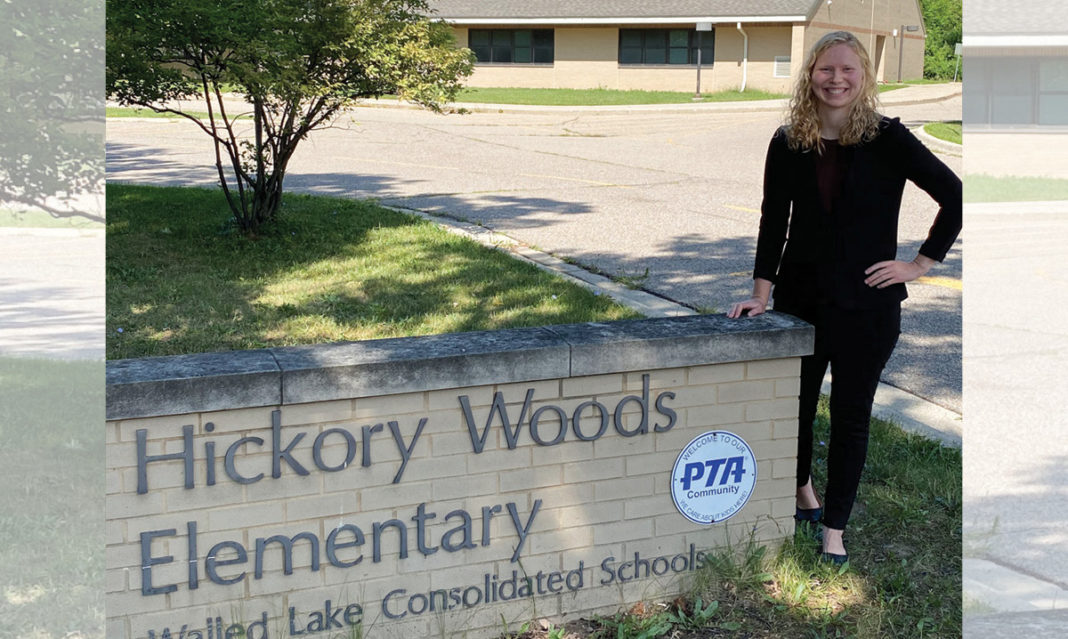 Megan Sidge posing with the sign for Hickory Woods Elementary