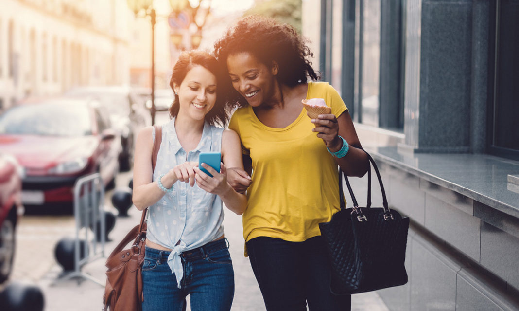 Two woman laughing while looking at a phone