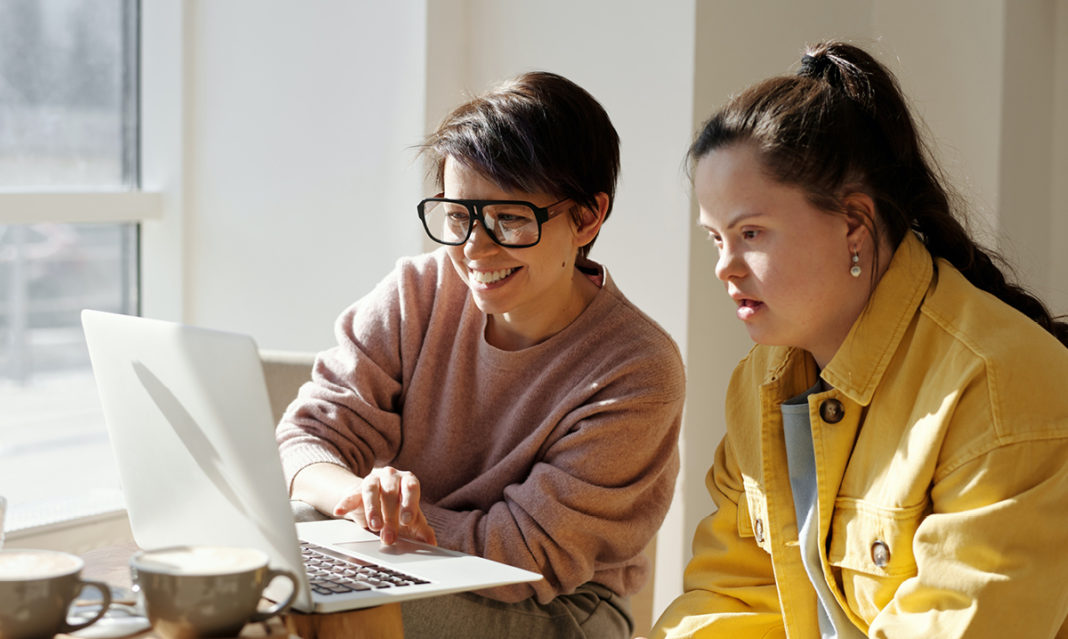 Woman helping a girl with Down's syndrome on a laptop