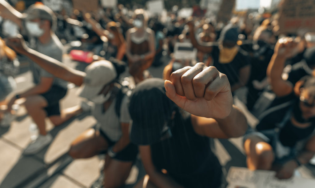 Group of people kneeling with fists in the air at a protest