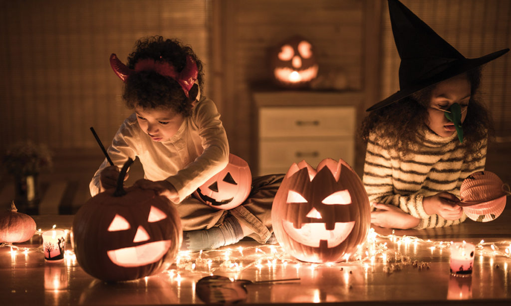 Two girls in costume carving pumpkins