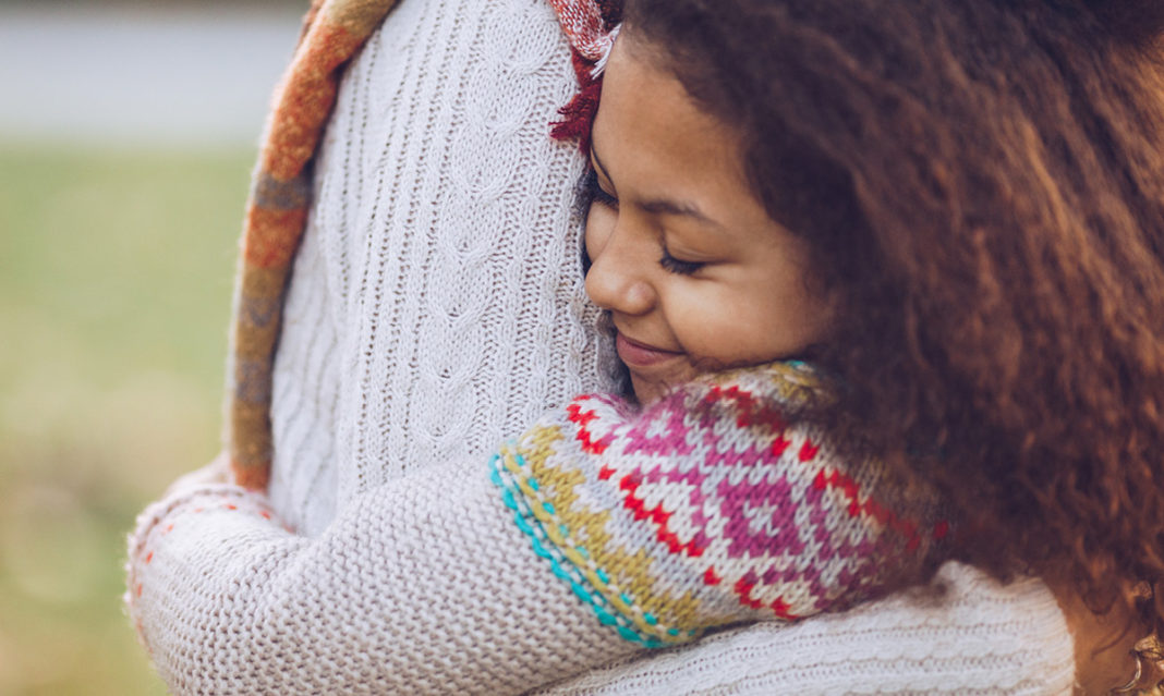 Close-up of a tween hugging someone in a white shirt