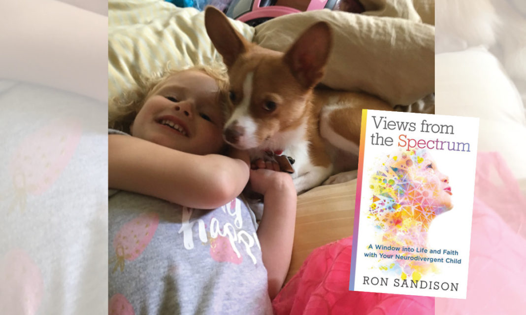 Makayla and her dog playing. Cover of Ron Sandison's latest book in the foreground