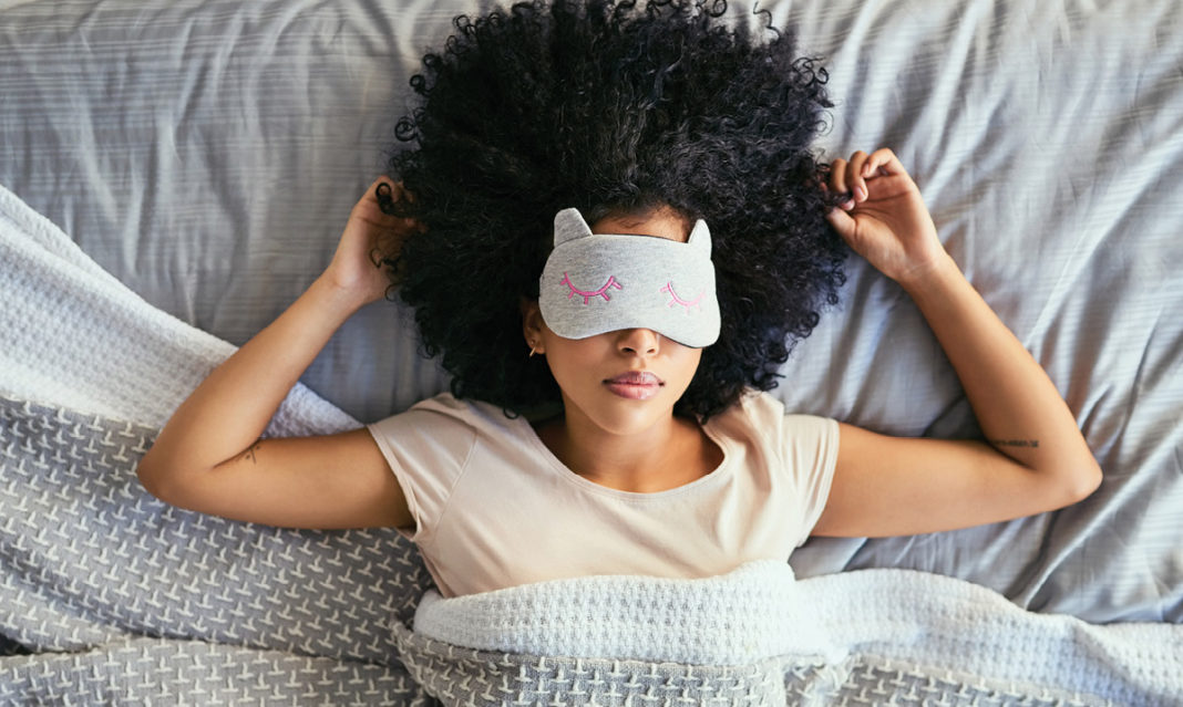 Woman in bed wearing a light-blocking eye mask