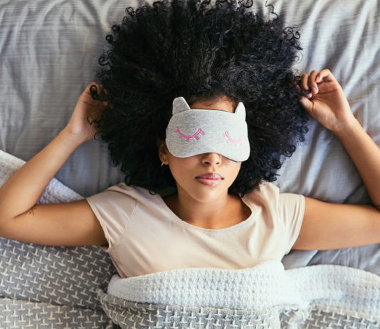 Woman in bed wearing a light-blocking eye mask