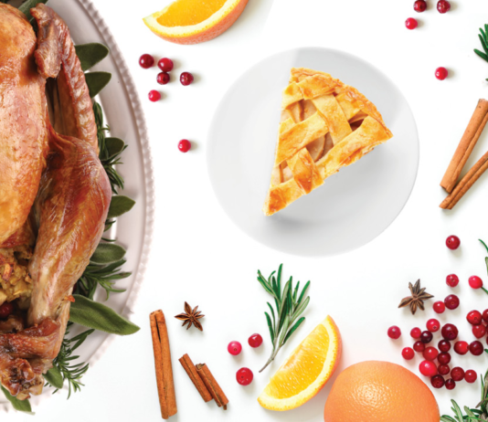 A turkey, cranberries, slice of pie and garnish on a white background