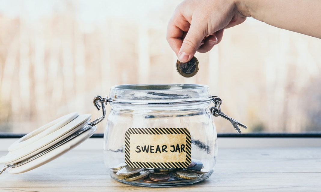 A hand dropping coins into a swear jar