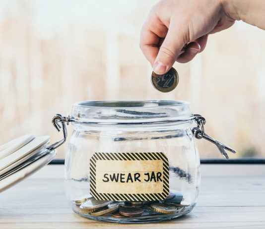 A hand dropping coins into a swear jar