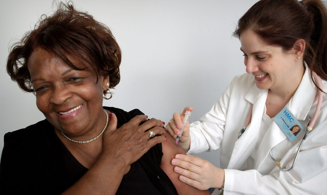 elderly woman getting a shot from a doctor